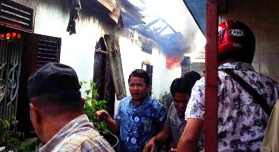 Warga memadamkan api di rumah Hakim Sihombing secara manual