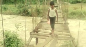 Seorang anak  melintasi rambin yang rusak di Desa Muara Kumpulan, Muara Sipongi