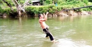 Seorang pria harus bergantung pada seutas tali hendak menyeberang Sungai Batang Gadis akibat ketiadaan titi gantung di Desa Muara Siambak Kecamatan Kotanopan.
