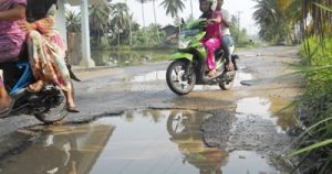 dua pengendara sepeda motor mengelakkan lobang tergenang di jalur Gunung Manaon-Adian Jior