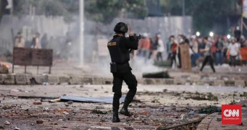 Seorang polisi mengarahkan senjata ke arah massa di Tanah Abang,